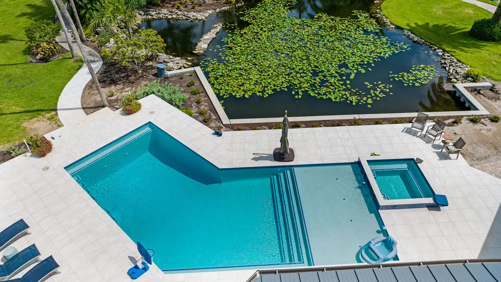 Aerial view of a custom built swimming pool next to a backyard pond