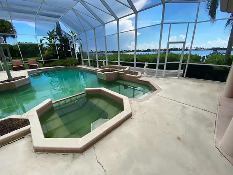 Empty pool area with green water