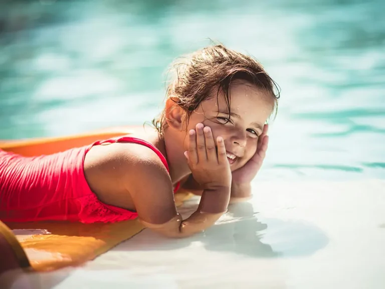 A young girl smiling while swimming in a pool