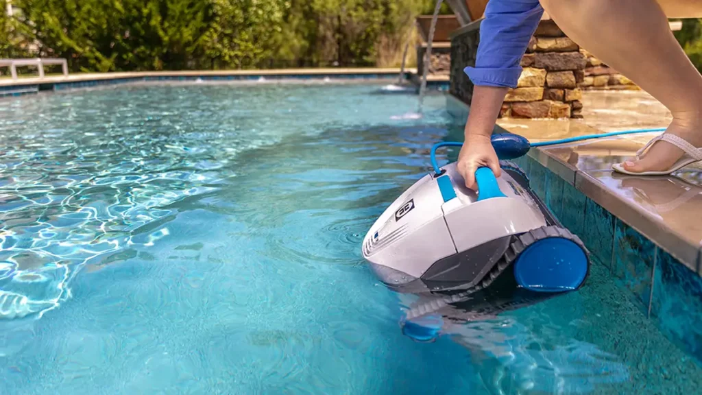 A woman placing a Hayward automatic pool cleaner in her pool