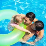 A couple swimming in their pool with their toddler