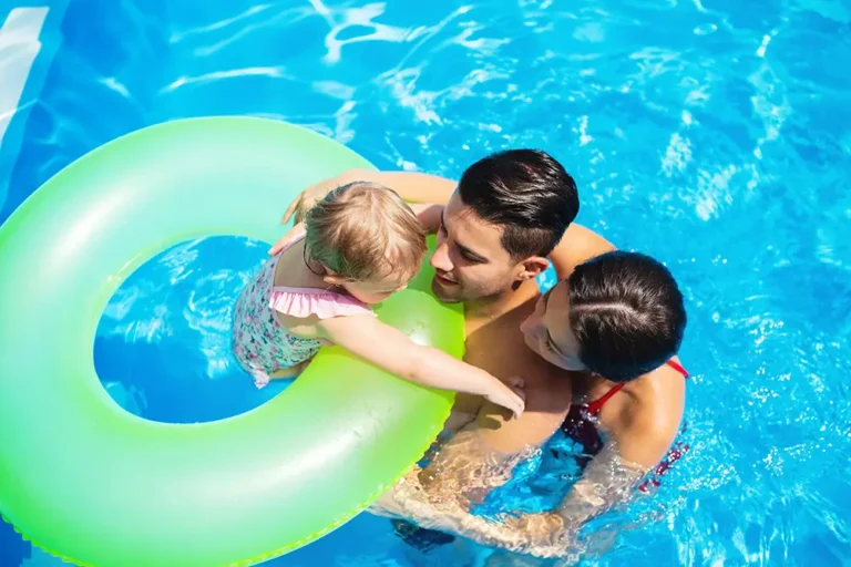 A couple swimming in their pool with their toddler