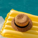 A raft in a pool with a sun hat sitting on top of it