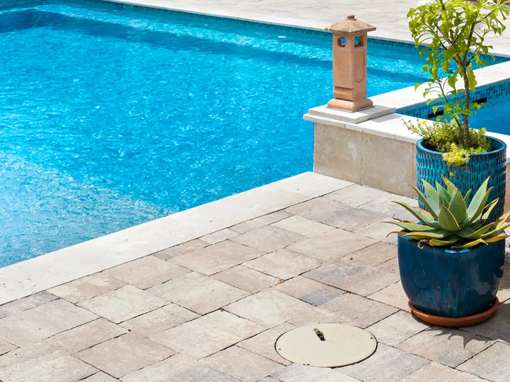 A crystal clear swimming pool with new patio pavers